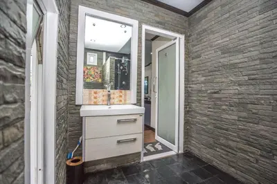 a bathroom with a sink and a mirror on a brick wall at Beautiful apartment in Ban Thalat Choeng Thale