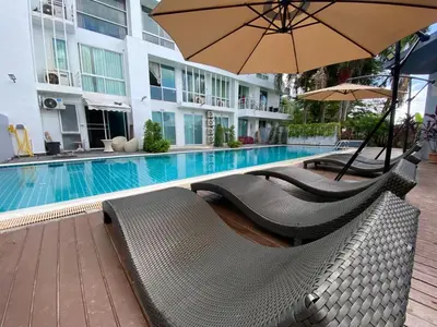a swimming pool with two chairs and an umbrella at Kris condo in Patong Beach