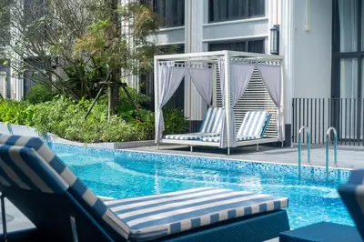 a swimming pool with two lounge chairs next to a swimming pool at Apartments Bellevue Lagoon Phuket near Laguna in Phuket