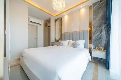 a bedroom with a large white bed and a chandelier at Apartments Bellevue Lagoon Phuket near Laguna in Phuket