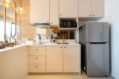 a kitchen with white cabinets and a refrigerator at Apartments Bellevue Lagoon Phuket near Laguna in Phuket