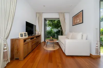 a living room with a white couch and a tv at Anchan 4 bedroom near Beach in Phuket