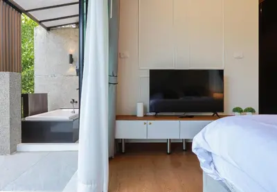 a bedroom with a tv and a bed and a bathroom at 3BR Pool Villa with Jacuzzi near Patong - 8 Guests in Kathu