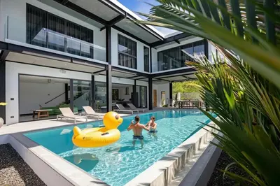 two people in the pool of a house with a yellow rubber duck in the water at Sleek Designed Sunset Garden Villa 05 - 4 BR with Salt Private Pool 12M in Ban Saiyuan (1)