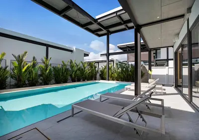 a swimming pool with two lounge chairs next to a house at Sleek Designed Sunset Garden Villa 05 - 4 BR with Salt Private Pool 12M in Ban Saiyuan (1)