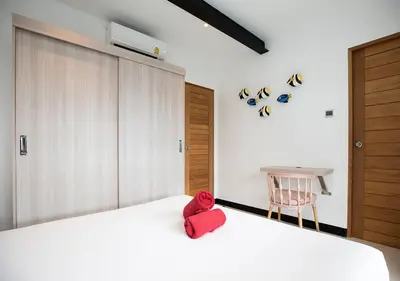 a bedroom with a white bed with a red object on it at Sleek Designed Sunset Garden Villa 05 - 4 BR with Salt Private Pool 12M in Ban Saiyuan (1)