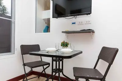 a table with two chairs and a tv on a wall at KUM house in Laguna Phuket