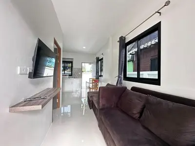 a living room with a brown couch and a flat screen tv at Layla house, Bang Tao beach in Ban Thalat Choeng Thale