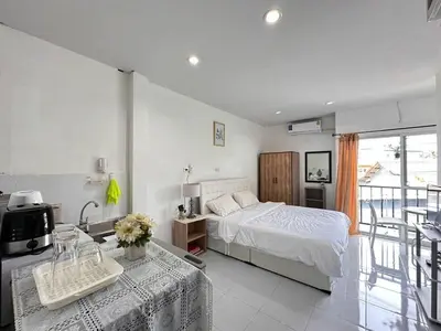 a white bedroom with a bed and a balcony at MAM house in a quiet and stylish location in Ban Thalat Choeng Thale