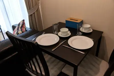 a black table with white plates and glasses on it at Cozy Apartment at Rawai with Pool Access in Phuket Town