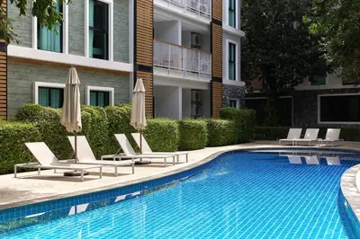 a swimming pool with chairs and umbrellas next to a building at Cozy Apartment at Rawai with Pool Access in Phuket Town