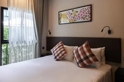 a bedroom with a bed with two pillows and a window at Cozy Apartment at Rawai with Pool Access in Phuket Town