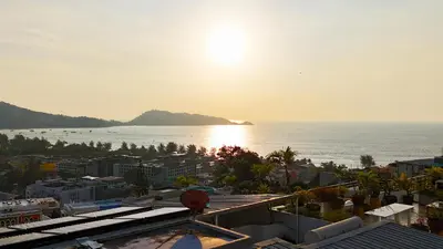 a view of a city and the ocean with the sun at Mali Villa 57 in Patong Beach
