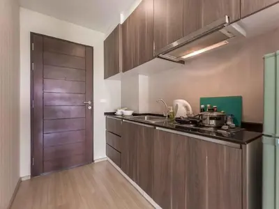 a kitchen with wooden cabinets and a sink and a door at Apartments in the NICE condominium on Bang Tao Beach in Ban Thalat Choeng Thale