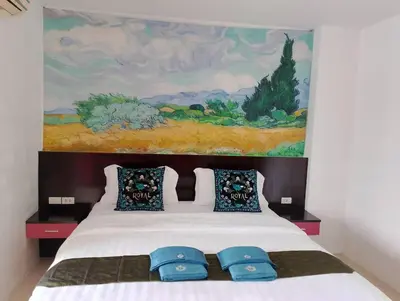 a bed with two blue pillows and a painting at sunflower \u4e00\u5367\u7cbe\u54c1\u5927\u5e8a\u623f\u5e26\u9633\u53f0 in Patong Beach