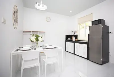 a kitchen with a white table and a refrigerator at NI houses in Ban Thalat Choeng Thale
