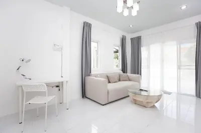 a white living room with a couch and a table at NI houses in Ban Thalat Choeng Thale