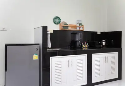 a kitchen with a black counter and a refrigerator at NI houses in Ban Thalat Choeng Thale