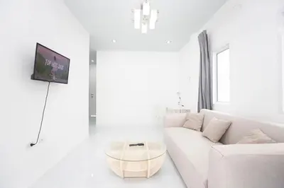 a white living room with a white couch and a table at NI houses in Ban Thalat Choeng Thale