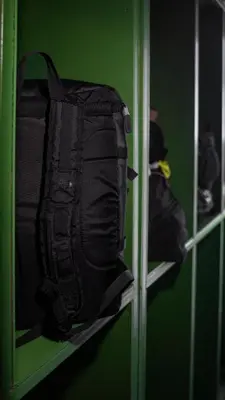 a black backpack on a shelf in a green room at The highdogs hostel in Phi Phi Don