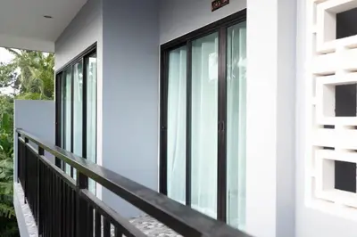 a balcony with glass doors on a house at Lovely OPTIC apartments on Bang Tao Beach in Ban Thalat Choeng Thale