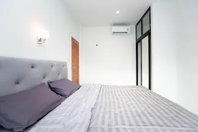 a bedroom with a large white bed with purple pillows at Lovely OPTIC apartments on Bang Tao Beach in Ban Thalat Choeng Thale