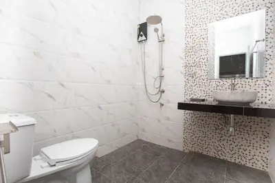 a white bathroom with a toilet and a sink at Lovely OPTIC apartments on Bang Tao Beach in Ban Thalat Choeng Thale