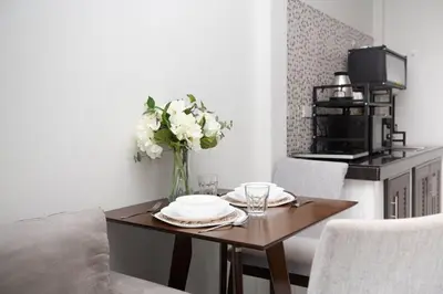 a dining room table with a vase of white flowers at Lovely OPTIC apartments on Bang Tao Beach in Ban Thalat Choeng Thale