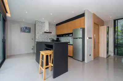 a kitchen with a stainless steel refrigerator and a wooden stool at Peaceful retreat at The Woods Natural Park in Kamala Beach