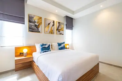 a bedroom with a large white bed with blue pillows at The S Villas in Laguna Phuket