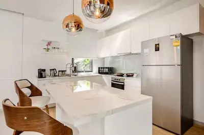 a kitchen with white cabinets and a white refrigerator at The S Villas in Laguna Phuket