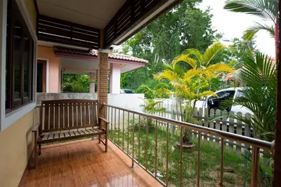 a porch with a bench on a balcony at Cozy PUY houses near Bang Tao Beach in Ban Thalat Choeng Thale
