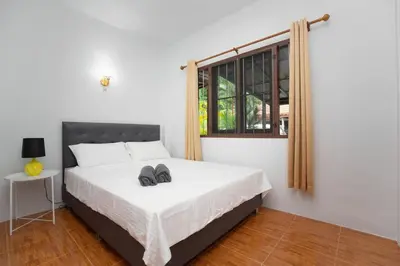 a bedroom with a bed with a pair of shoes on it at Cozy PUY houses near Bang Tao Beach in Ban Thalat Choeng Thale