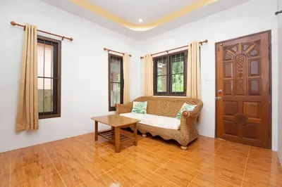 a room with a chair and a table and a door at Cozy PUY houses near Bang Tao Beach in Ban Thalat Choeng Thale