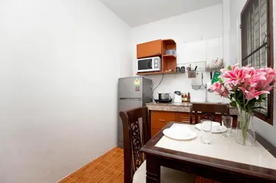 a kitchen with a table with a vase of pink flowers at Cozy PUY houses near Bang Tao Beach in Ban Thalat Choeng Thale