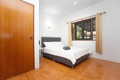 a bedroom with a bed and a window and a door at Cozy PUY houses near Bang Tao Beach in Ban Thalat Choeng Thale