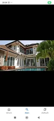 a large house with a palm tree in front of it at Suriyasom Villa 5 in Thalang
