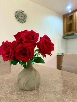 a vase filled with red roses sitting on a table at Suriyasom Villa 5 in Thalang