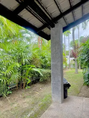 a bench sitting under a building with palm trees at Suriyasom Villa 5 in Thalang
