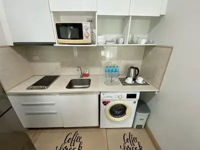 a small kitchen with a microwave and a washing machine at The Bay cliff By Tris in Patong Beach