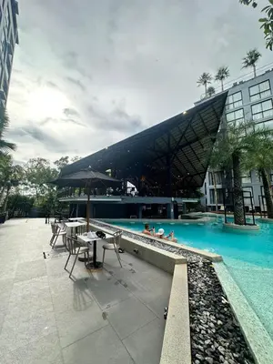 a swimming pool with tables and chairs and a building at CityGate Kamala 1 bedroom by Ere B312 in Kamala Beach