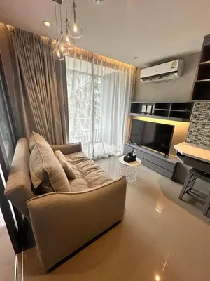 a living room with a couch and a television at CityGate Kamala 1 bedroom by Ere B312 in Kamala Beach