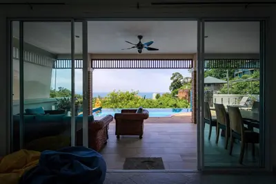 a living room with a sliding glass door to a patio at Luxury Seaview Villa, Infinity Pool, Sunset in Karon Beach