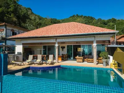 a house with a swimming pool in front of a house at Luxury Seaview Villa, Infinity Pool, Sunset in Karon Beach