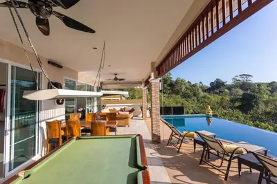 a swimming pool with chairs and a pool table at Luxury Seaview Villa, Infinity Pool, Sunset in Karon Beach