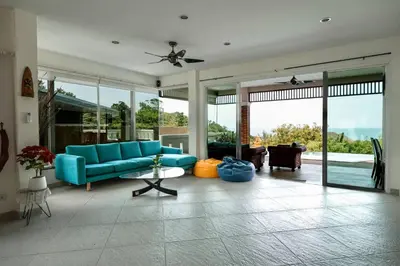 a living room with a blue couch and large windows at Luxury Seaview Villa, Infinity Pool, Sunset in Karon Beach