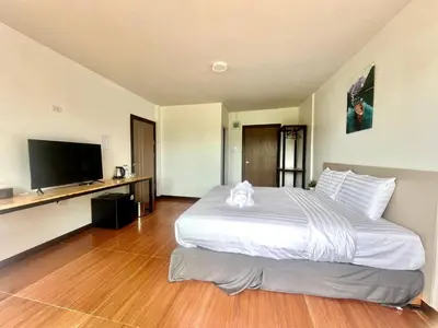 a bedroom with a large bed and a flat screen tv at Lucky 9 Airport Hotel Phuket in Nai Yang Beach