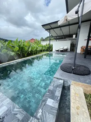 a swimming pool in a villa with an umbrella at Sakhu Art Villa in Nai Yang Beach