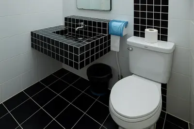 a bathroom with a toilet and a black tiled floor at Chic Boutique Hotel, Patong in Patong Beach