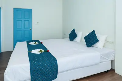 a white bed with blue pillows and a tie on it at Chic Boutique Hotel, Patong in Patong Beach